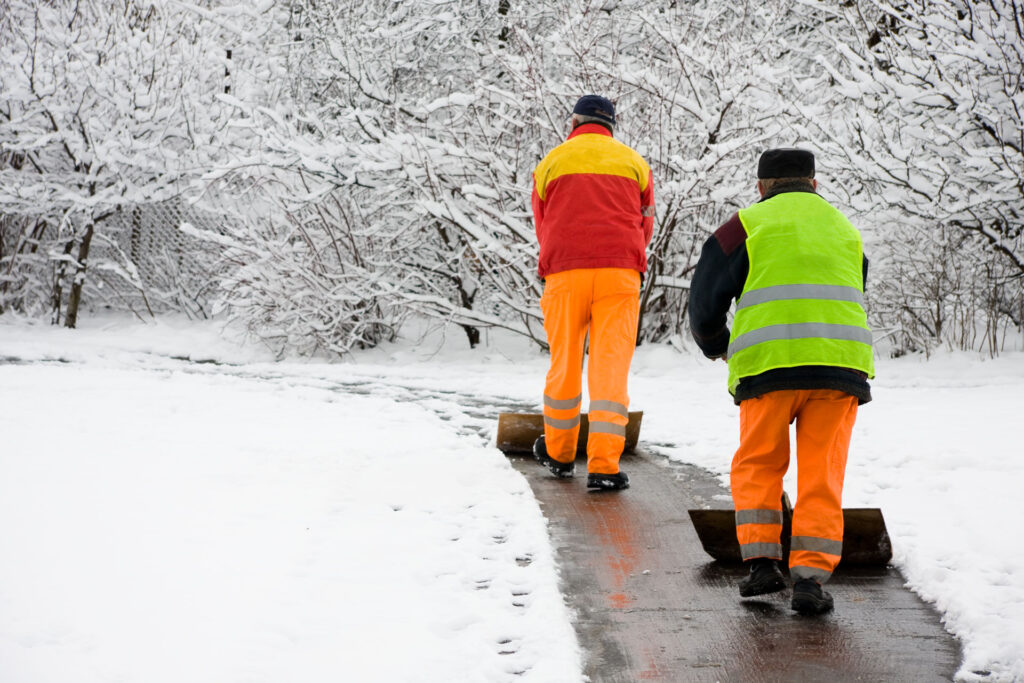 Die Männer schippen Schnee